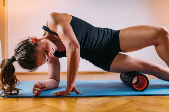 Woman using a foam roller on a yoga mat in a home setting