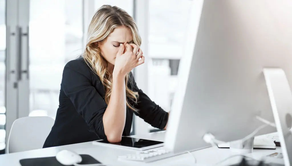 Woman experiencing headache and mental fatigue while working at a desk