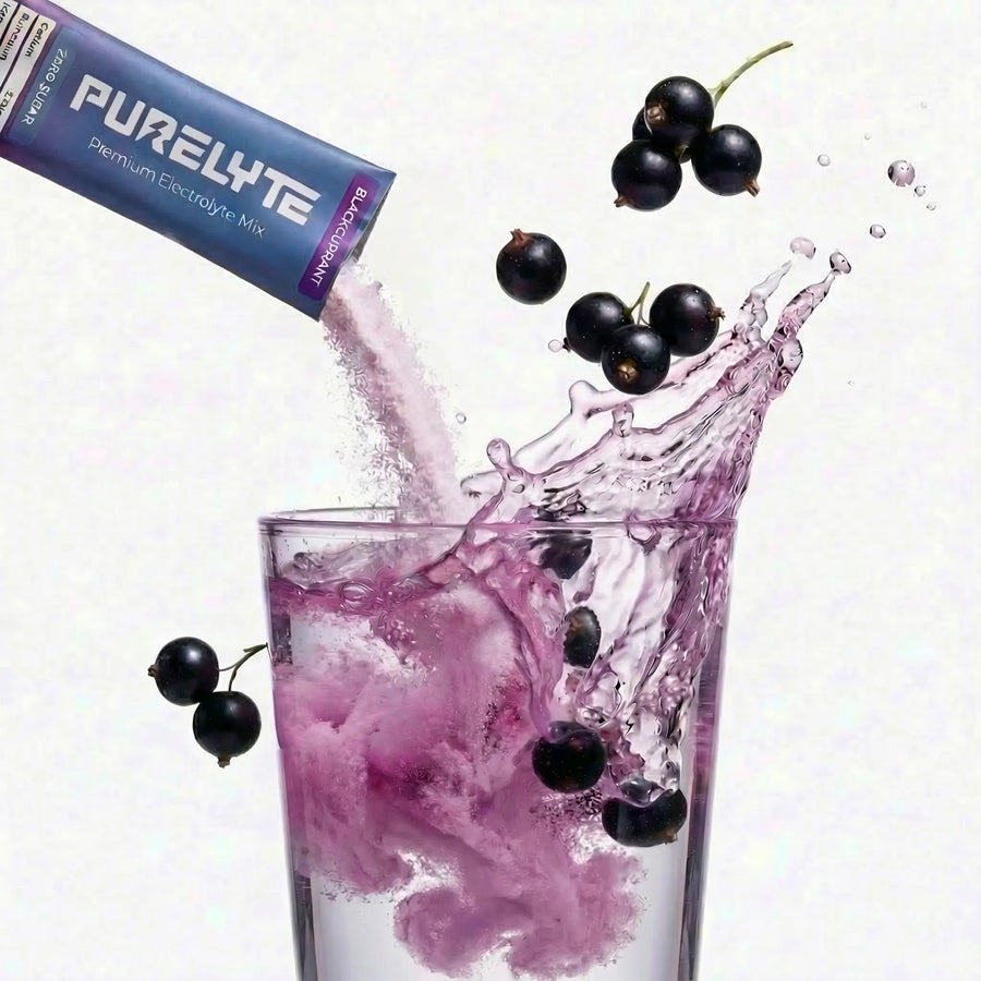 Purelyte blackcurrant electrolyte mix with blackcurrants and a glass of Purelyte powder mixing in water on a white background