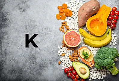 Assorted fruits, vegetables, and grains high in potassium on a gray background with a letter 'K' above them.